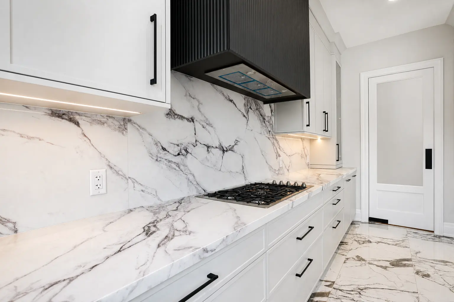 Gas cooktop with full-slab marble backsplash and pantry door