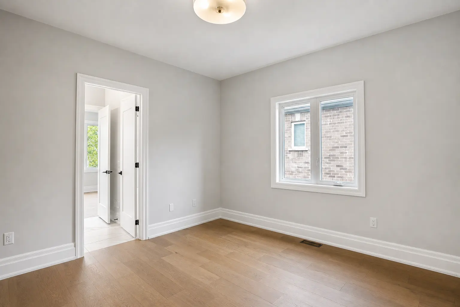 Bright bedroom with oak floors and ensuite doorway