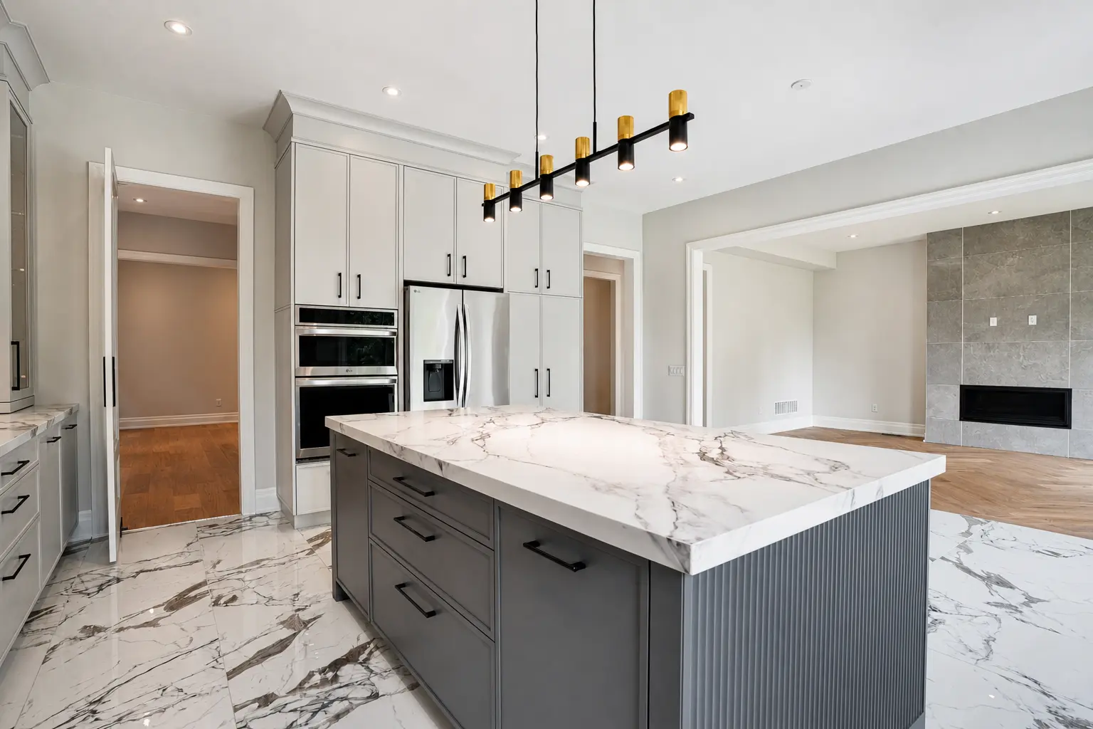 Kitchen open to the family room with built-in wall oven and fireplace beyond
