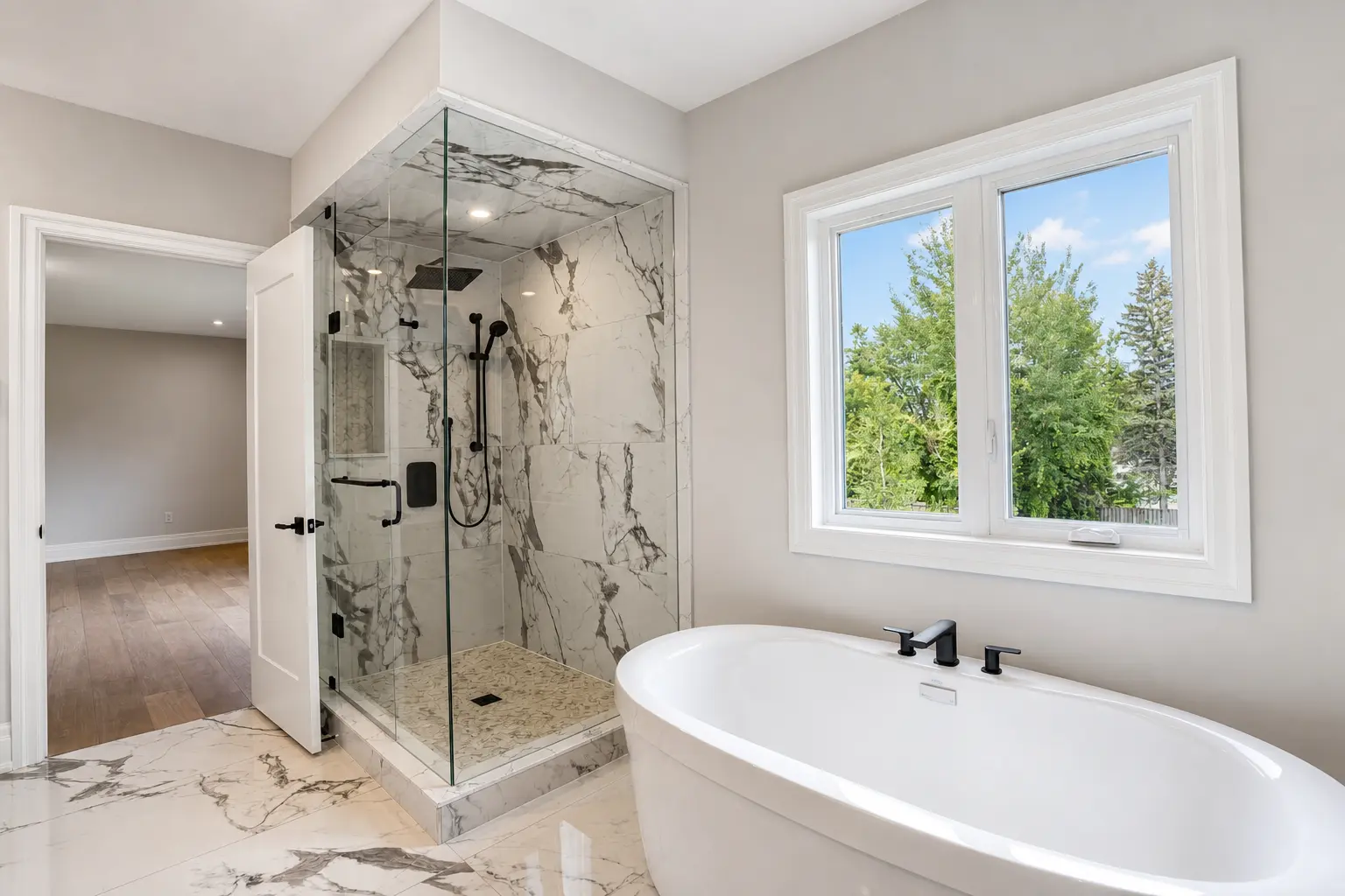 Primary ensuite with freestanding soaker tub and marble glass shower
