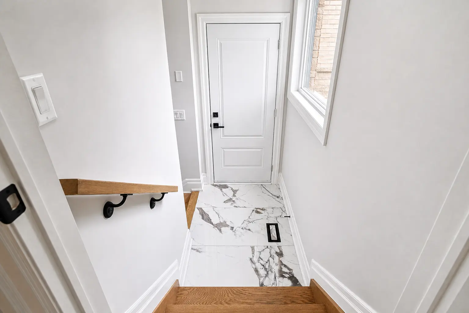 Side entry landing with marble tile floor and oak shelf